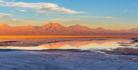 Panoramic view of a salt-flat with salt-lake and volcanoes in the background in the Atacama desert,...