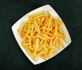 flat lay or top view of a plate of french fres on a dark green textured background
