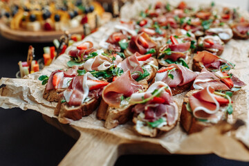 Festive Buffet. An assortment of cold cuts and canapes on wooden skewers. Cocktail reception at the party. catering with meats, fruits, cheeses and sandwiches. - obrazy, fototapety, plakaty