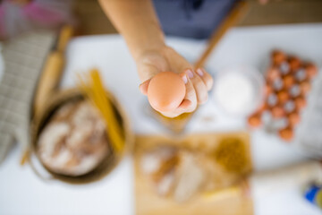 Female hand holding an egg above ingredients on a table