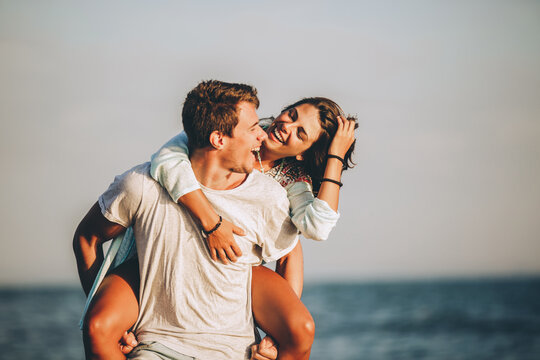 Young man giving piggyback ride to girlfriend on beach.