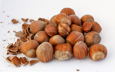Hazelnuts, some of them shelled, on a white background.
