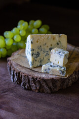 
blue cheese on a wooden frame on a wooden background with white grapes in rustic style