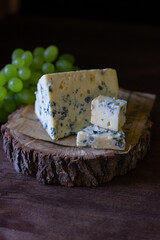 
blue cheese on a wooden frame on a wooden background with white grapes in rustic style