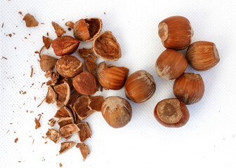 Hazelnuts, some of them shelled, on a white background.