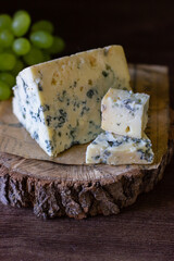 
blue cheese on a wooden frame on a wooden background with white grapes in rustic style