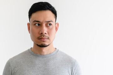 Asian man in a grey t-shirt is looking at the empty space on isolated white background.