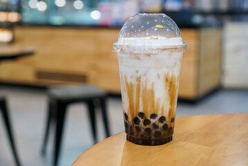 A plastic cup of fresh milk and brown sugar boba or bubble drinks on wooden table. (isolated, copy space)