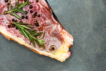 Steak with rosemary and pepper on a black background.