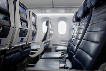 Empty dark blue seats with screens in the back inside an airplane