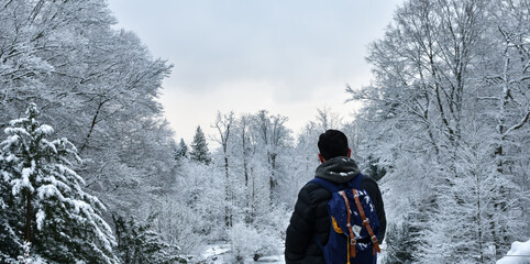 young man with backpack on his back looking at nature in snowy landscape, Concept person in winter forest