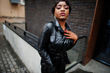 Fashionable beautiful african american woman posing in black leather jacket at street. Earring in the nose.