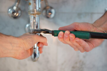 Young plumber fixing a sink in bathroom