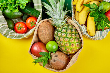 Eco shopping bags with organic fruits and vegetable on yellow background.