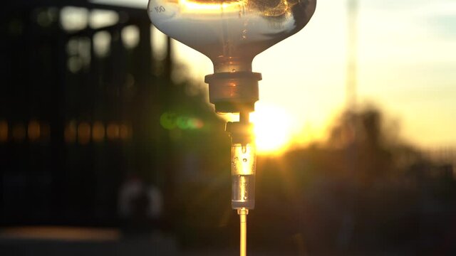 Closeup of IV drip and sunset.  Intravenous saline solution, IV loading dose.