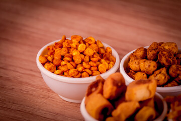 indian namkeen on wooden table,Indian Namkeen or snacks in white bowl on wooden background, close up of indian Namkeen snacks beautiful footage,Sev murmura,chanadal,shing bhujia,mix chavana