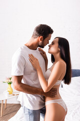 Naklejka premium sexy young couple hugging and looking at each other in bedroom