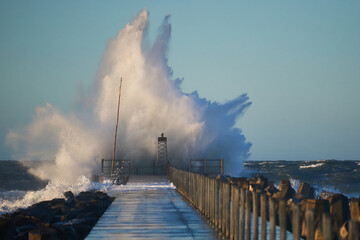 Dramatic, strong waves and foam spray hit the pier in Vorupoer during storm on the North Sea coast...