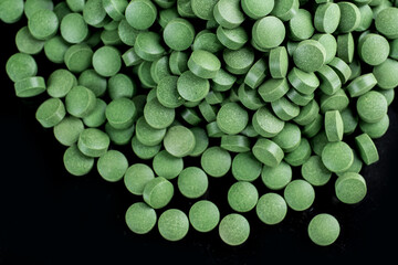 chlorela freshwater algae in a pill on a black background..