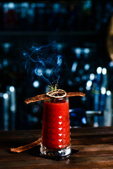 Alcoholic cocktail Bloody Mary in a glass in the form of a skull and smoke from a branch of thyme...