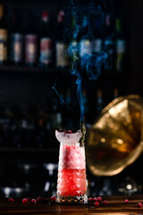 Glass with pink drink and dry ice smoke, bubbles, pink cold cocktail with ice and smoke