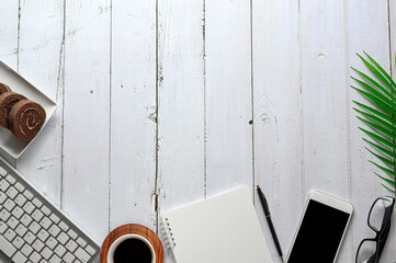 White wooden floor with keyboard, clock, glasses, cup with coffee. In preparation for working in the office or at home