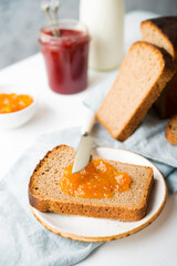 Fresh homemade bread with jam and milk, homemade simple food, light background