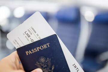 Male hand holding American passport and airplane ticket