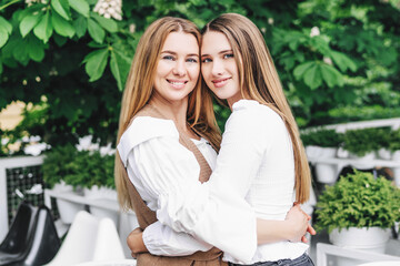 Fototapeta premium Two beautiful blonde women, a mother and a daughter, they hug and smile at the camera. Women's day