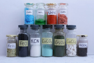 There are many glass jars with different colored crystalline substances, chemical reagents.