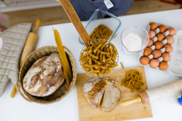 Uncooked fusilli on wooden pasta strainer above ingredients on a table