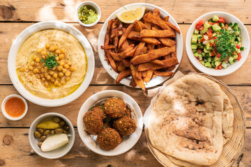 Israel traditional food hummus with chickpea and parsley, vegetarian falafel, pita, salad, fries...