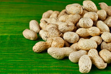 Peanuts in shell on a green board. Texture of nuts on a wooden old table. Lots of nuts in a pile.