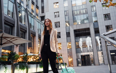 Town style clothes. Beautiful young european woman is outdoors in the city at daytime