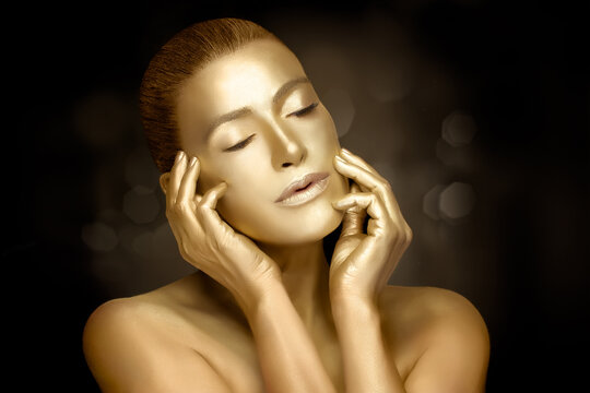 Gold cosmetics. Female model touching golden skin. 24k gold for skin care treatment