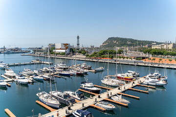 Obraz premium Many white yachts are moored in the port of Barcelona on a sunny summer day