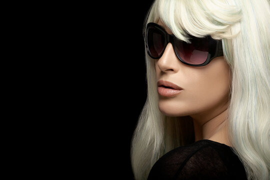 Fashion portrait of an attractive blond woman in sunglasses on black background