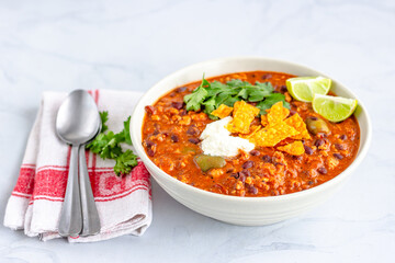 Mexican Chicken Chili Garnished with Cilantro, Saour Cream, Lemon and Chips Close Up Photo