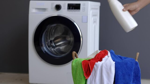A man with a bottle of laundry detergent About to pour the detergent into the washing machine
