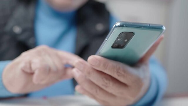 Close up old female hands using smartphone, sit-down arm resting on the table, retirement leisure activity, technology mobile application, in app purchase and media, checking emails, e-book reader