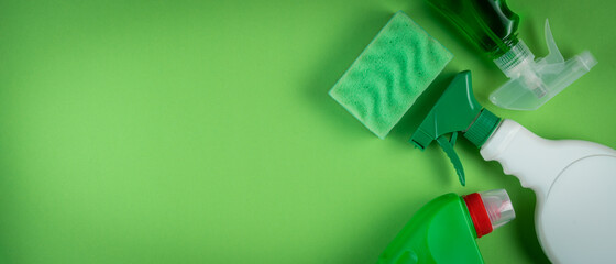 Cleaning supplies on green background, top view