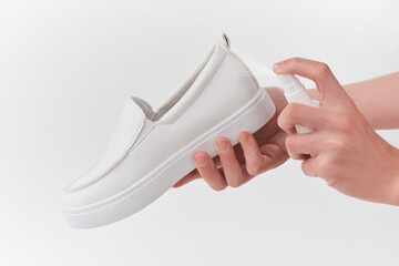 Close-up on a white leather loafer being sprayed with an antiseptic