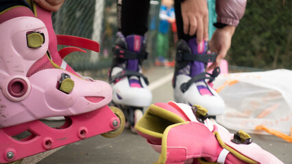 Selective Focus on setting of laces on pink and purpel inline skates, starting to skating