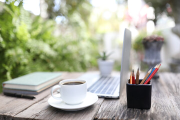 White coffee cup and laptop with pencil stationary outdoor work space