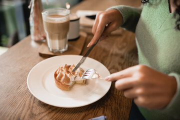cropped view of african american woman holding cutlery near tart on plate