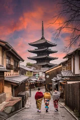 Fototapeten (Selective focus) Three unidentified women wearing kimono are walking on the path leading to the to the Kiyomizu-dera Temple (defocused in the distance) during a stunning sunset. Kyoto, Japan. © Travel Wild