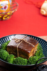 Dong Po Pork meat in a blue plate with broccoli with red background.