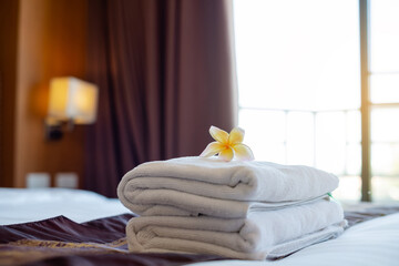 Obraz na płótnie Canvas A hotel maid stacked towels on the bed and placed flowers on the towels in a hotel room