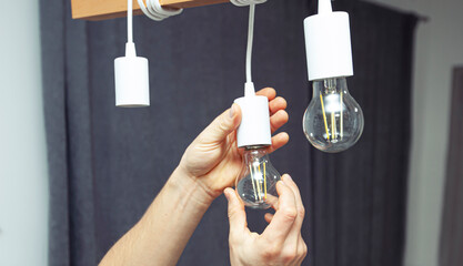 The electrician is installing the led light bulbs into the chandelier