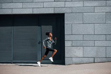 Fototapeta na wymiar Active runner. Young african american woman in sportive clothes have workout outdoors at daytime